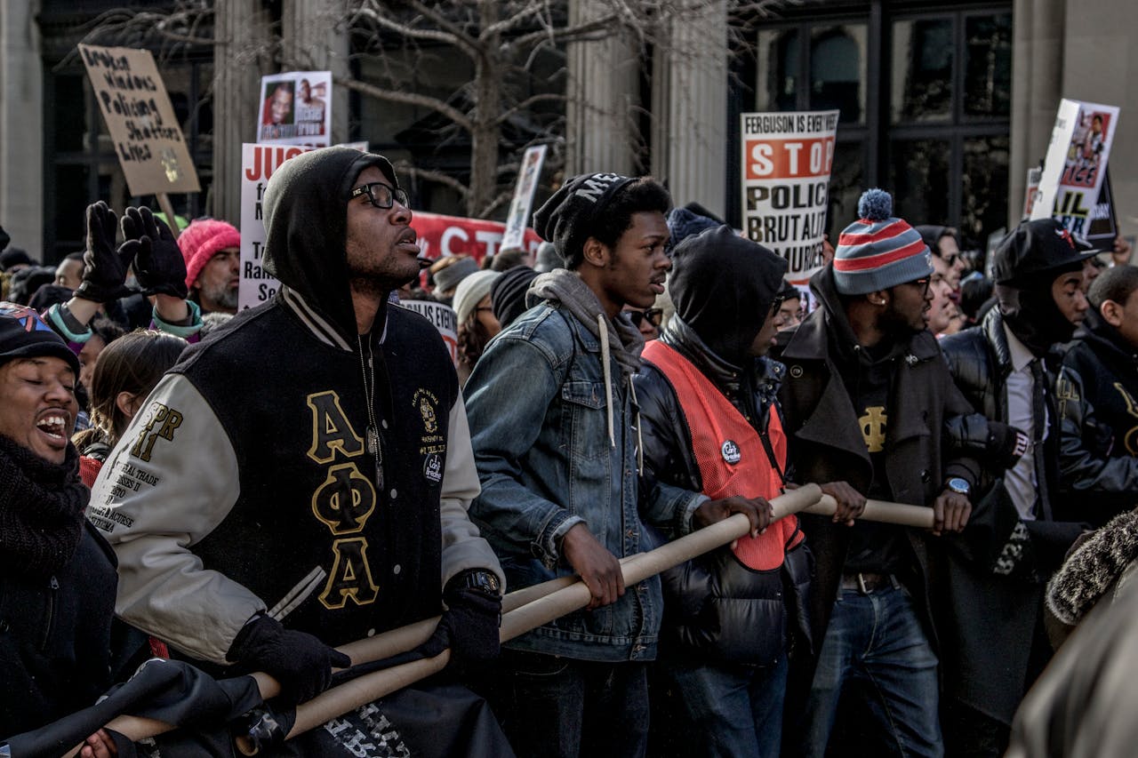 Protesters march in New York City against police brutality, holding signs and banners.