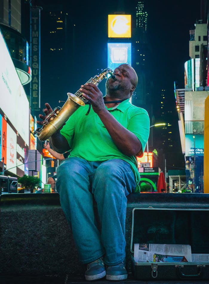 Street musician playing saxophone in vibrant Times Square, NYC by night.
